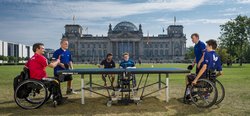 Die Para-TT-Spieler des BS Berlin spielen auf der Rasenfläche vor dem Reichtstag Tischtennis.